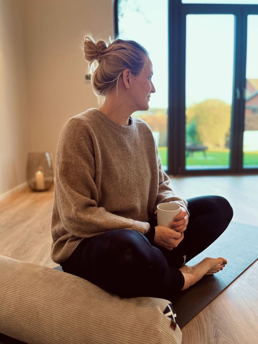 Entspannte Frau im Schneidersitz auf einer Yoga-Matte